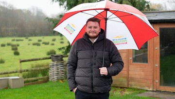 BROLLY GOOD: Liam smiles through the rain after his postcode came up