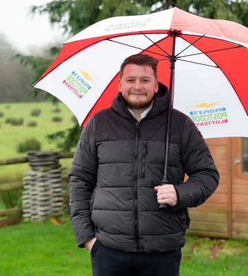 BROLLY GOOD: Liam smiles through the rain after his postcode came up