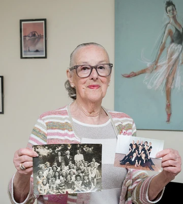 Victoria holds up photos of her dance classes from 1947 and 2022