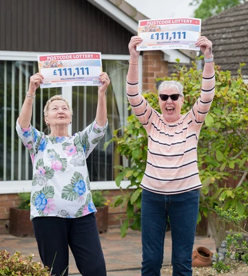 Next door neighbours Olga and Linda hold their winning cheques aloft